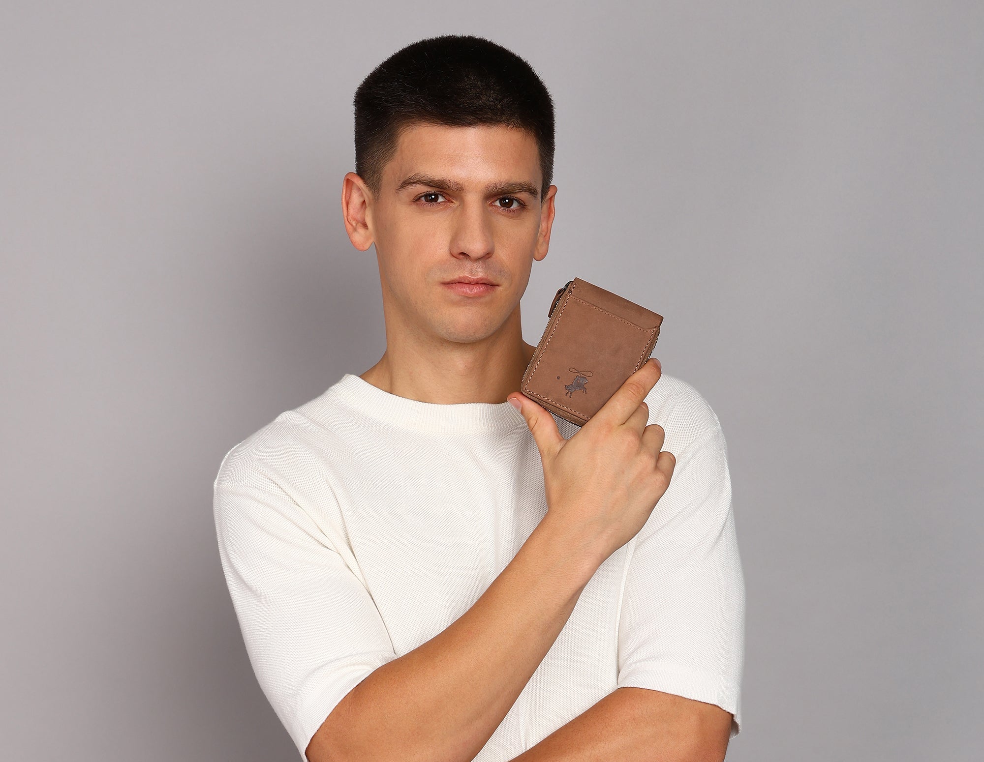 Man holding a brown wallet against a gray background